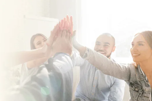A team of colleagues joining in a high-five in a bright office